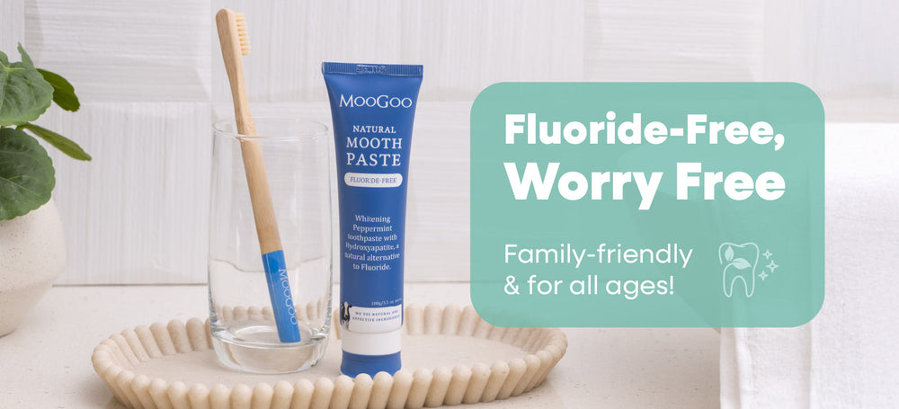 An image of MooGoo's Flouride-Free Moothpaste sitting beside a glass and tooth brush on a bathroom vanity