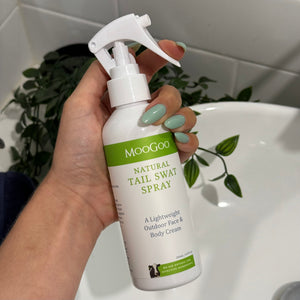 MooGoo Tail Swat Spray shown against a bathroom sink in hand, multipurpose natural spray to hydrate skin and provide outdoor protection against insects for all ages.