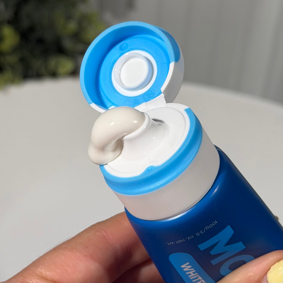 MooGoo Fluoride-Free Peppermint Whitening toothpaste tube with toothpaste being squeezed out, held by a hand.