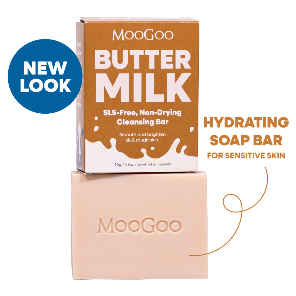 MooGoo Butter Milk SLS-Free Non-Drying Cleansing Bar shown with its brown cardboard box and the pale peach soap bar stacked below. A blue circular 'NEW LOOK' badge appears on the left, and text on the right reads 'HYDRATING SOAP BAR FOR SENSITIVE SKIN'. Hydrating cleansing bar for dry skin, natural oils, SLS free and gentle on sensitive skin.